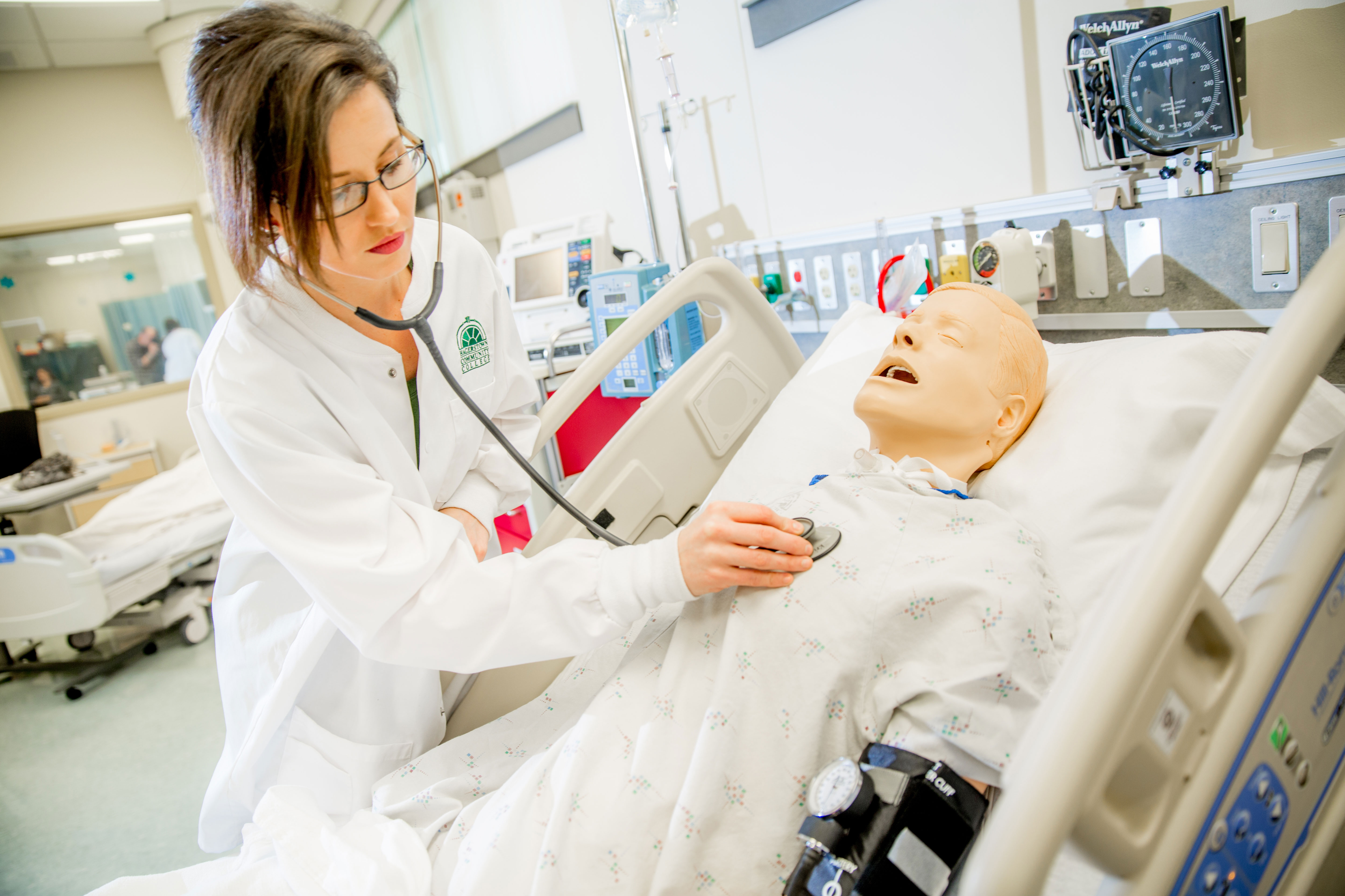 Nursing student taking pulse on model patient in nursing lab