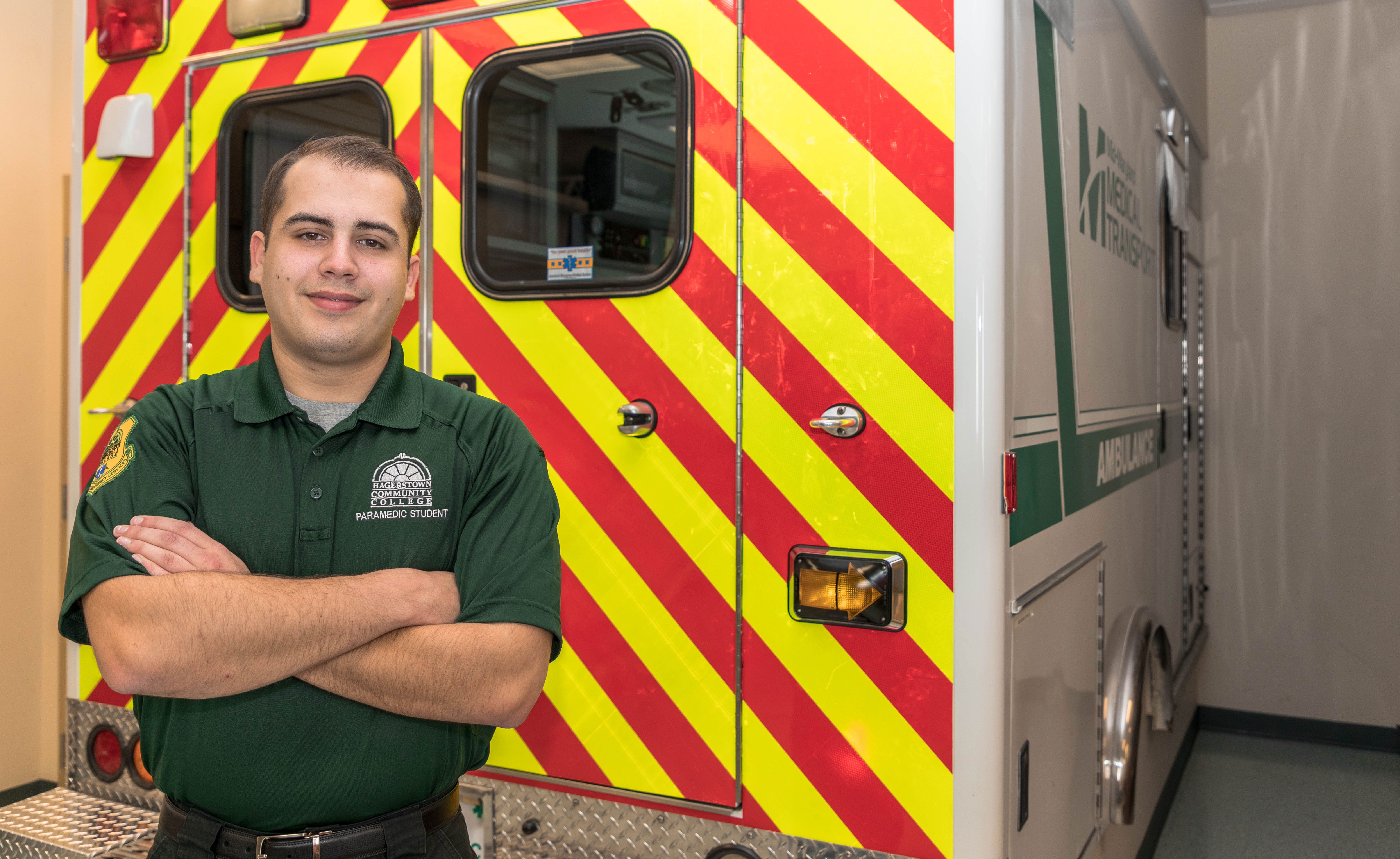 EMT student posing in front of ambulance in classroom